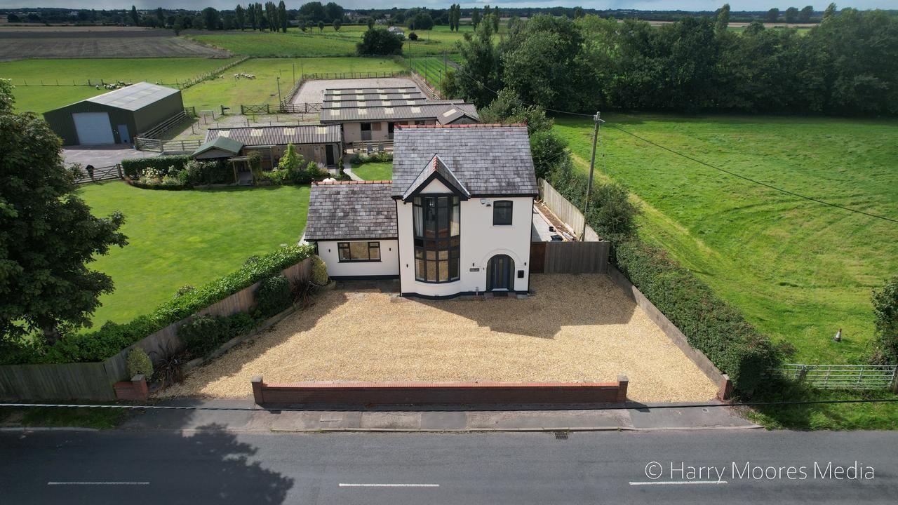 Aerial photograph of a white cottage with a gravel drive and outbuildings