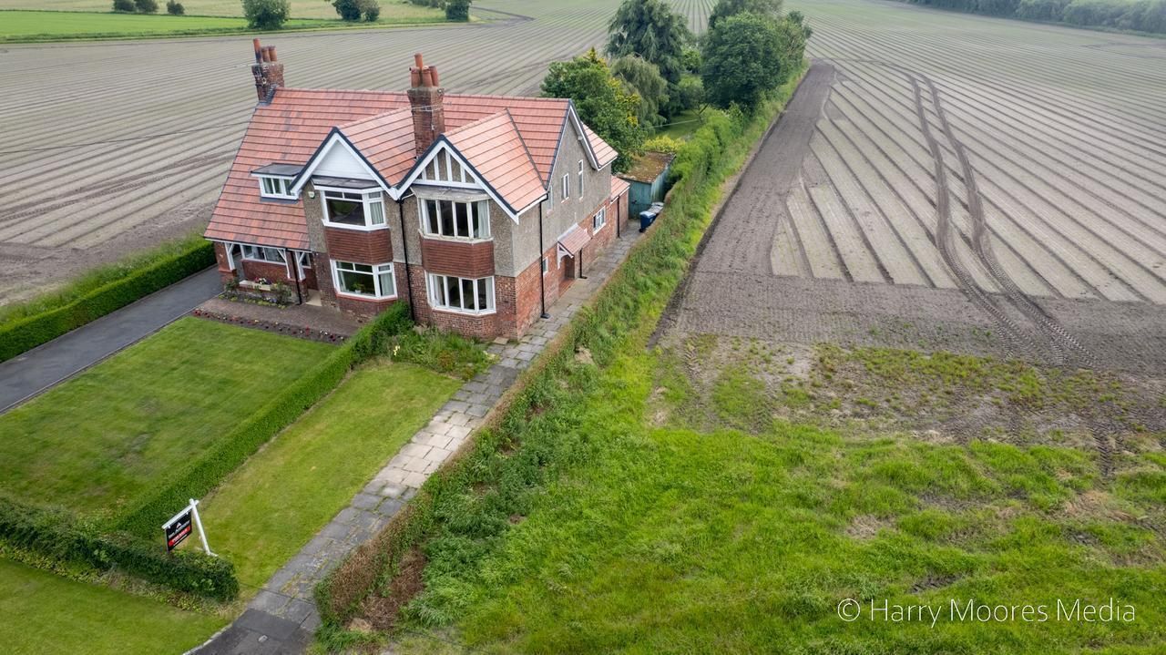 Aerial photograph of a semi-detached house with a for-sale board, farmland behind