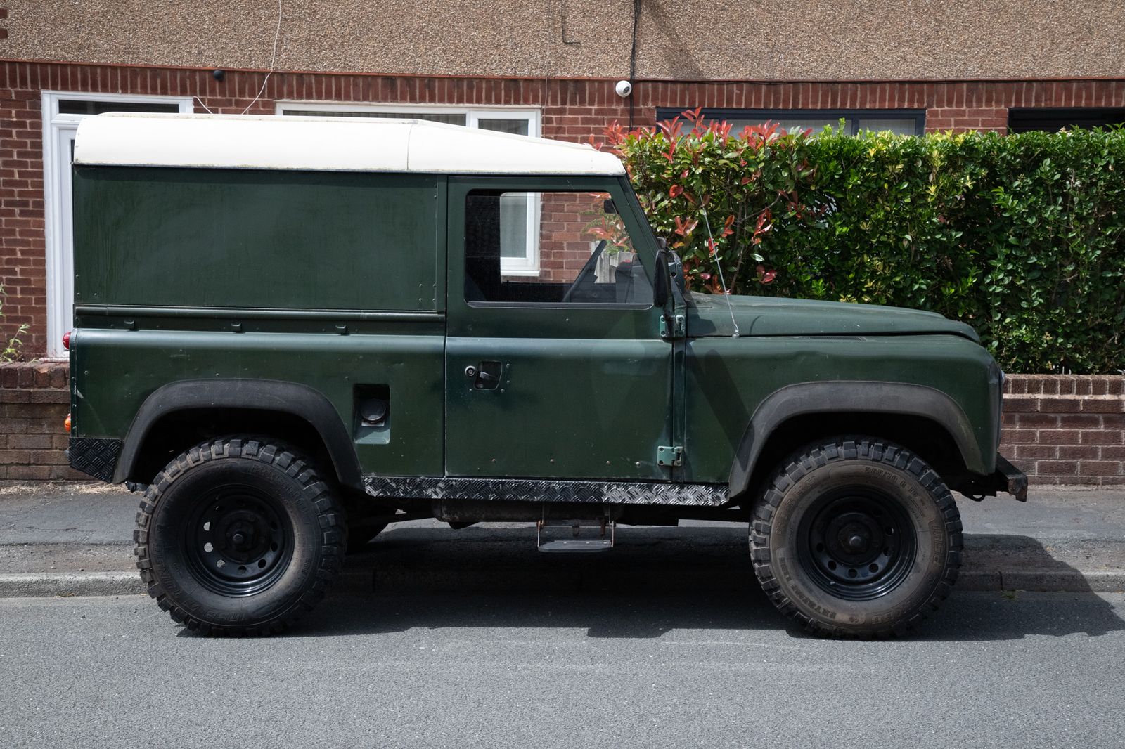 A green Land Rover Defender in side profile