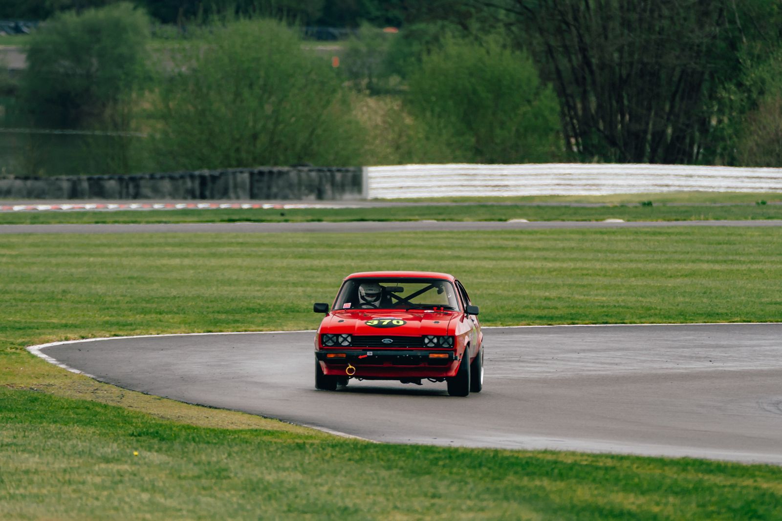 A red Capri head-on with the driver's helmet visible through the windscreen