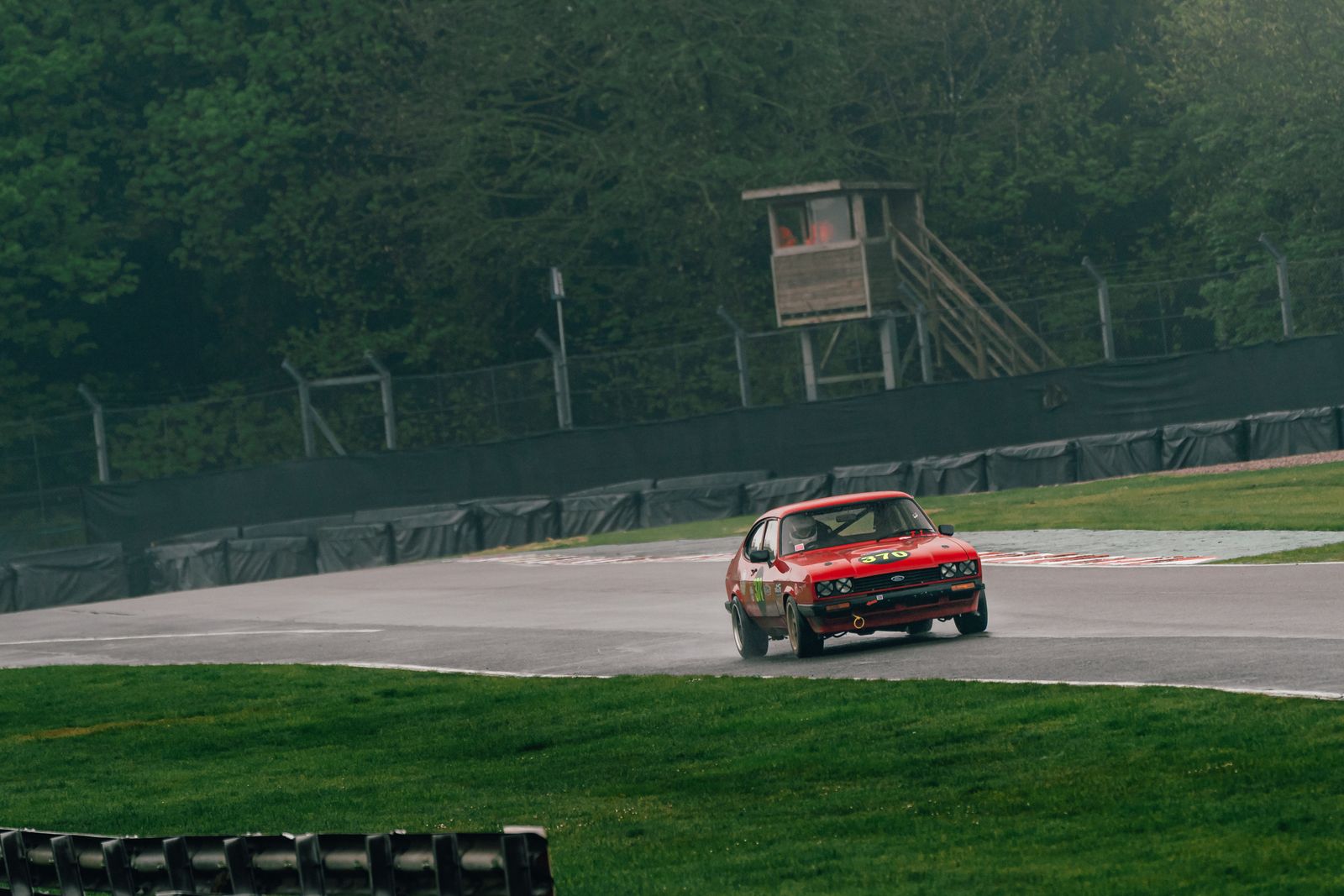 A red Capri on track with the marshals' tower and catch fencing behind